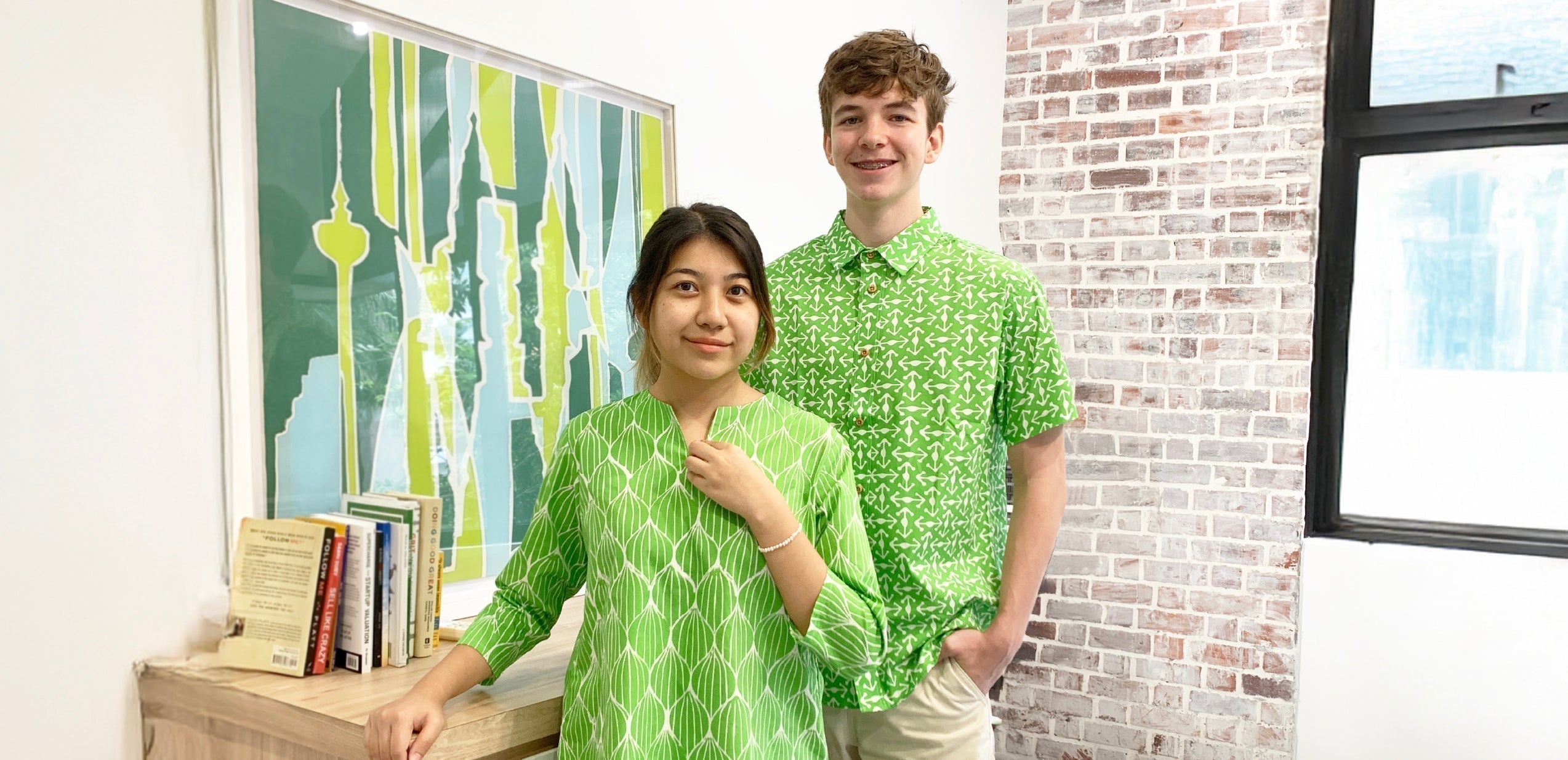 Man and woman in Deloitte green batik outfits — Bawang print baju kedah and Kompas print shirt.