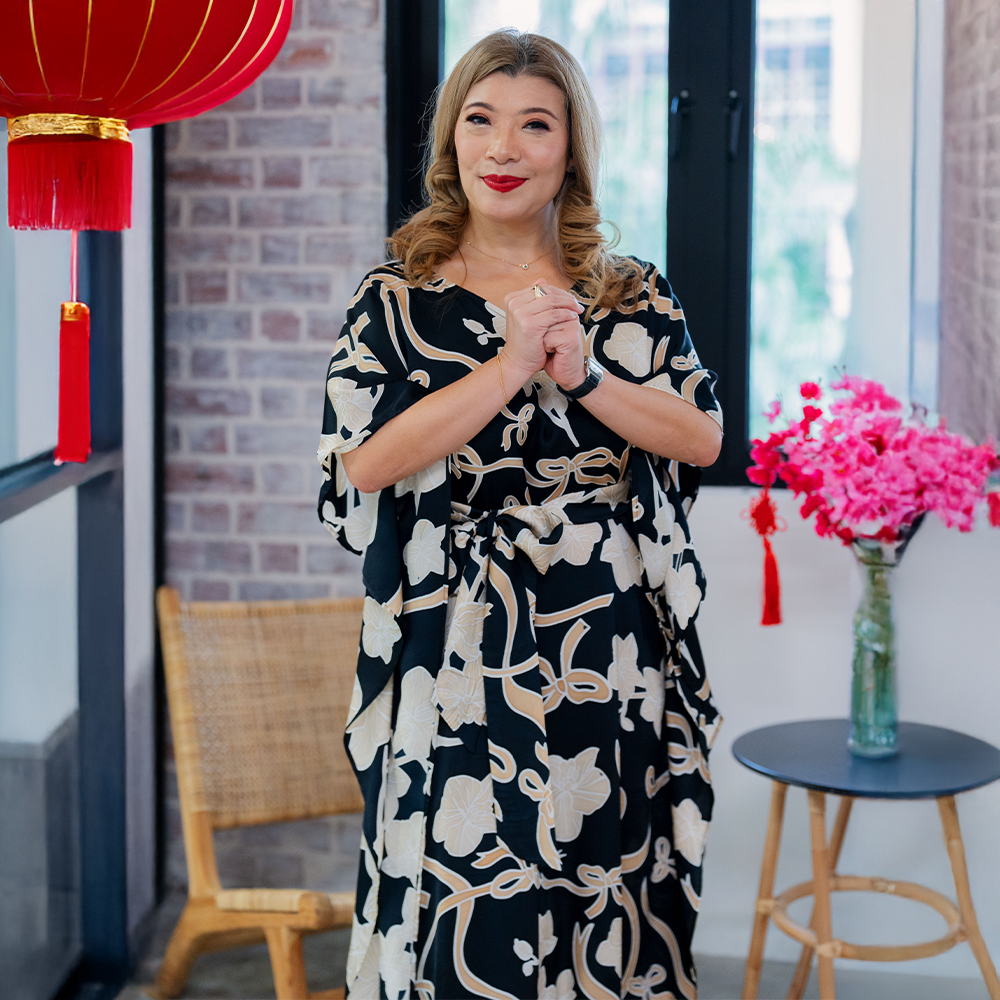a woman posing in a CNY setting in a batik caftan dress