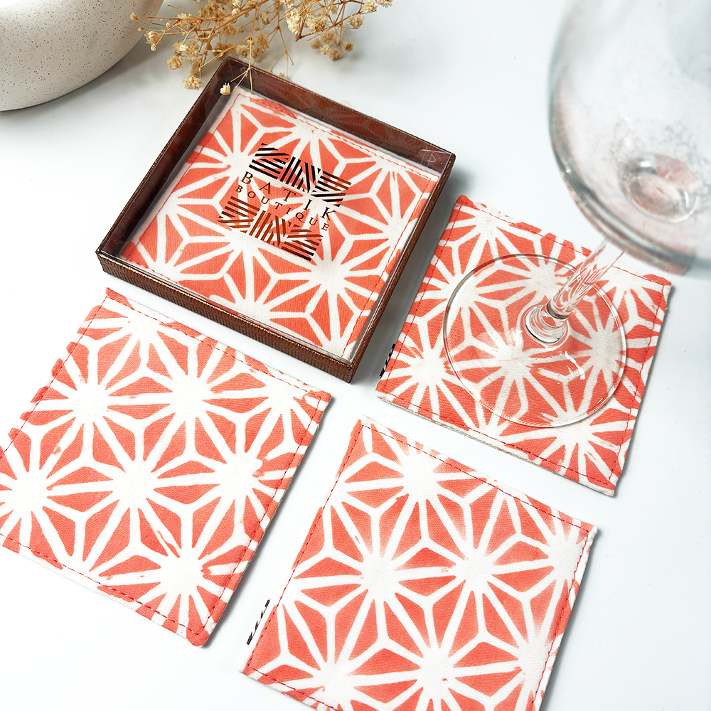 Artisan-crafted peach batik coasters with starburst pattern, set of four coasters, Square cotton coasters featuring peach firework batik design, reversible sides in matching tones, handcrafted by Malaysian artisans. Peach and white batik coasters in starburst motif, reversible fabric with Batik Boutique logo box, ideal for home décor or gifting. Perfect for  drinking, parties, Events
Stocking stuffer