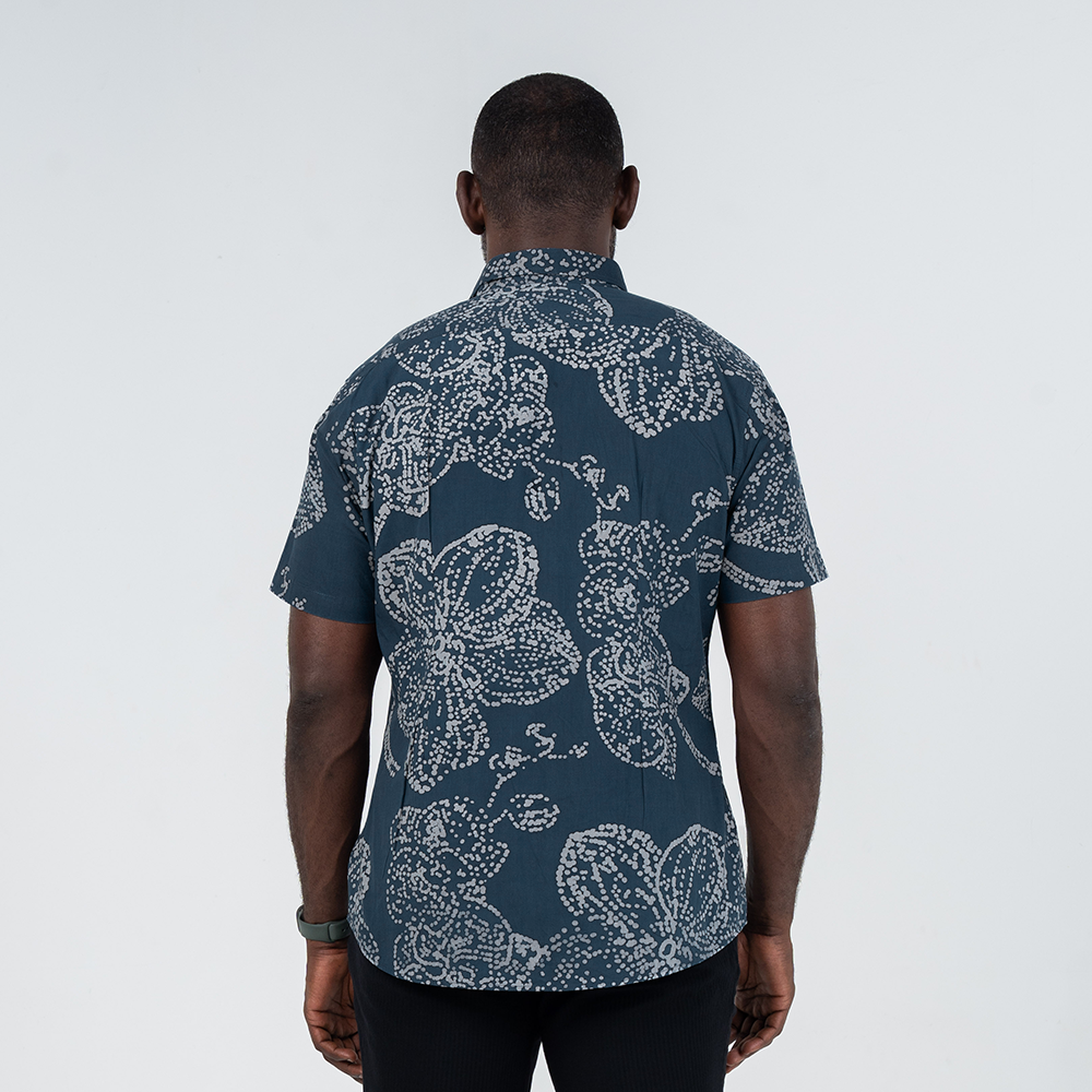 Back view of men's short-sleeved batik shirt in navy with hand-painted orchid motif, showcasing modern darts for an untucked fit