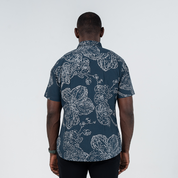 Back view of men's short-sleeved batik shirt in navy with hand-painted orchid motif, showcasing modern darts for an untucked fit