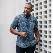 Man wearing navy batik orchid shirt styled casually outdoors, highlighting its modern Malaysian craftsmanship