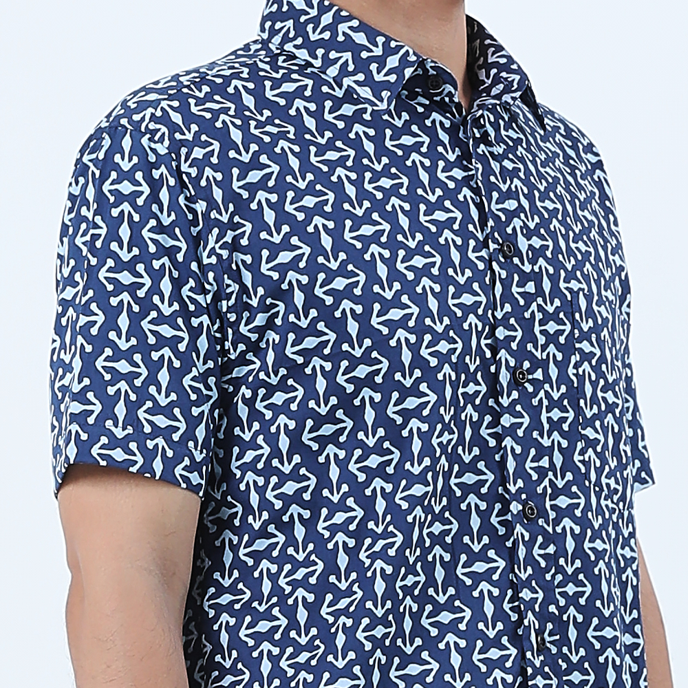 a closeup of a man wearing a batik shirt in the pattern navy kompas against a white background
