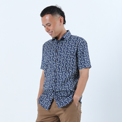 a man wearing a batik shirt in the pattern navy kompas against a white background