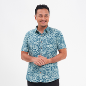 a man wearing a batik shirt in the pattern teal ukir against a white background