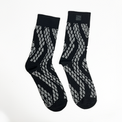 a batik inspired socks in the pattern black snakeskin against a white background