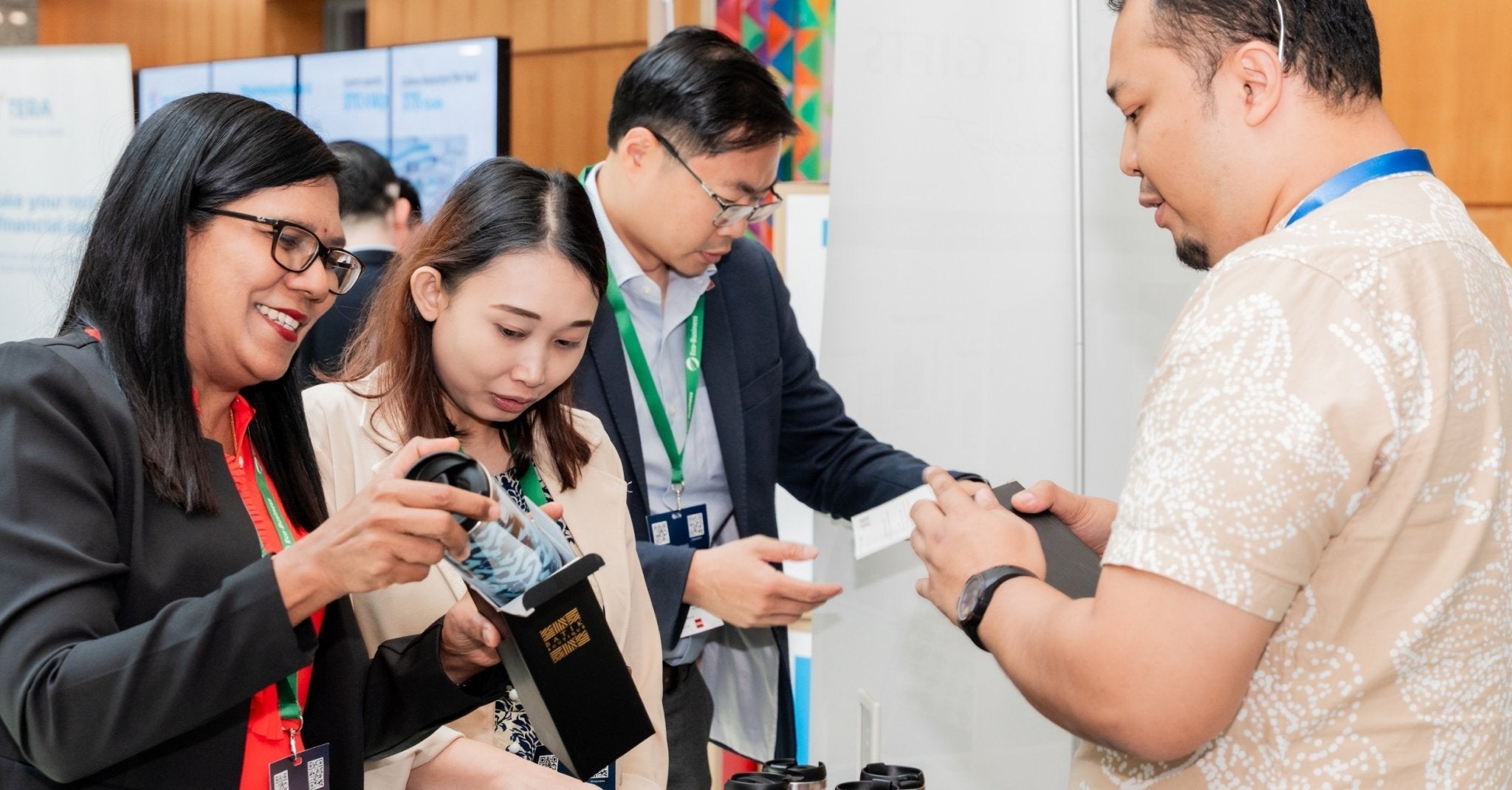 Corporate guests unboxing Batik Boutique's custom batik tumblers at an event booth, guided by a Batik Boutique team member.