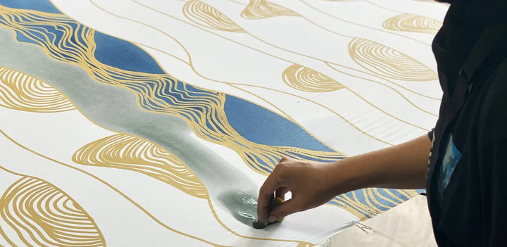 An artisans painting batik print name bukit in blue colour