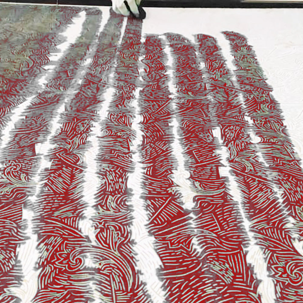 An artisan is painting on drfitwood pattern in red color