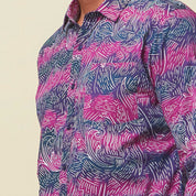 A closeup photo of man standing in front of beige background wearing maroon long sleeved shirt facing front