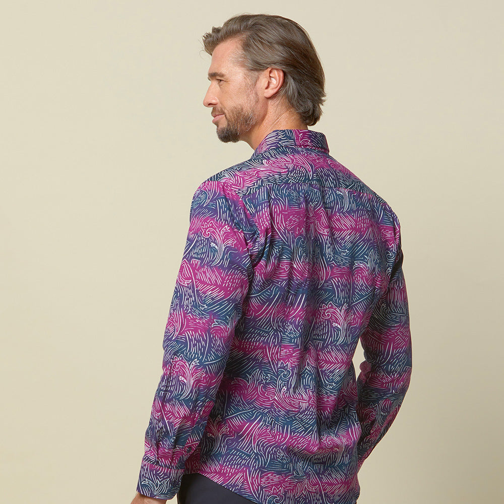 A photo of man standing in front of beige background wearing maroon long sleeved shirt facing front