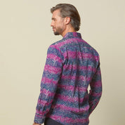 A photo of man standing in front of beige background wearing maroon long sleeved shirt facing front