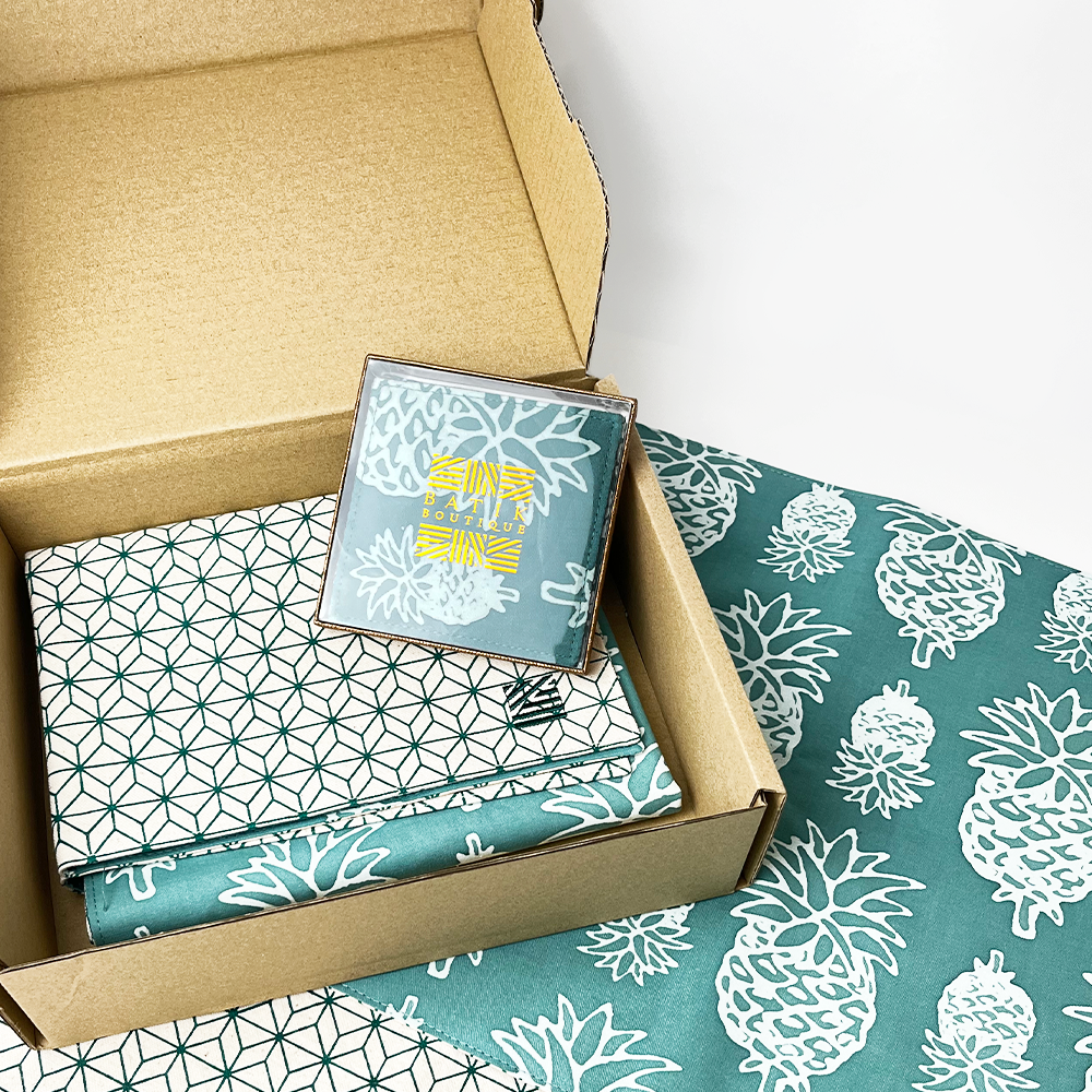 a photo detailing what's in a homeware box in the pattern turquoise pineapple including a set of coasters and placemats