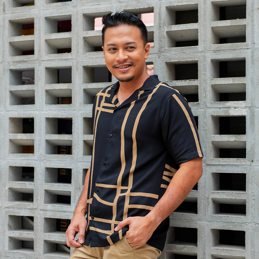 A man wearing a cuban batik shirt made of batik in the pattern black ecru in a lifestyle photo
