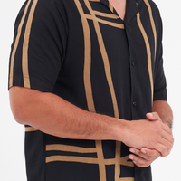 A closeup shot of a batik cuban shirt in the pattern black ecru against a white background