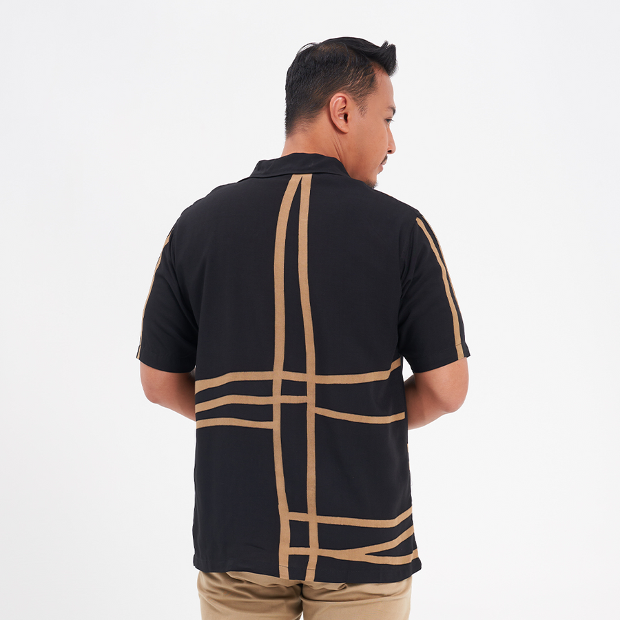 a photo of a man posing with his back to the camera against a neutral background to showcase the details on the back of the batik shirt