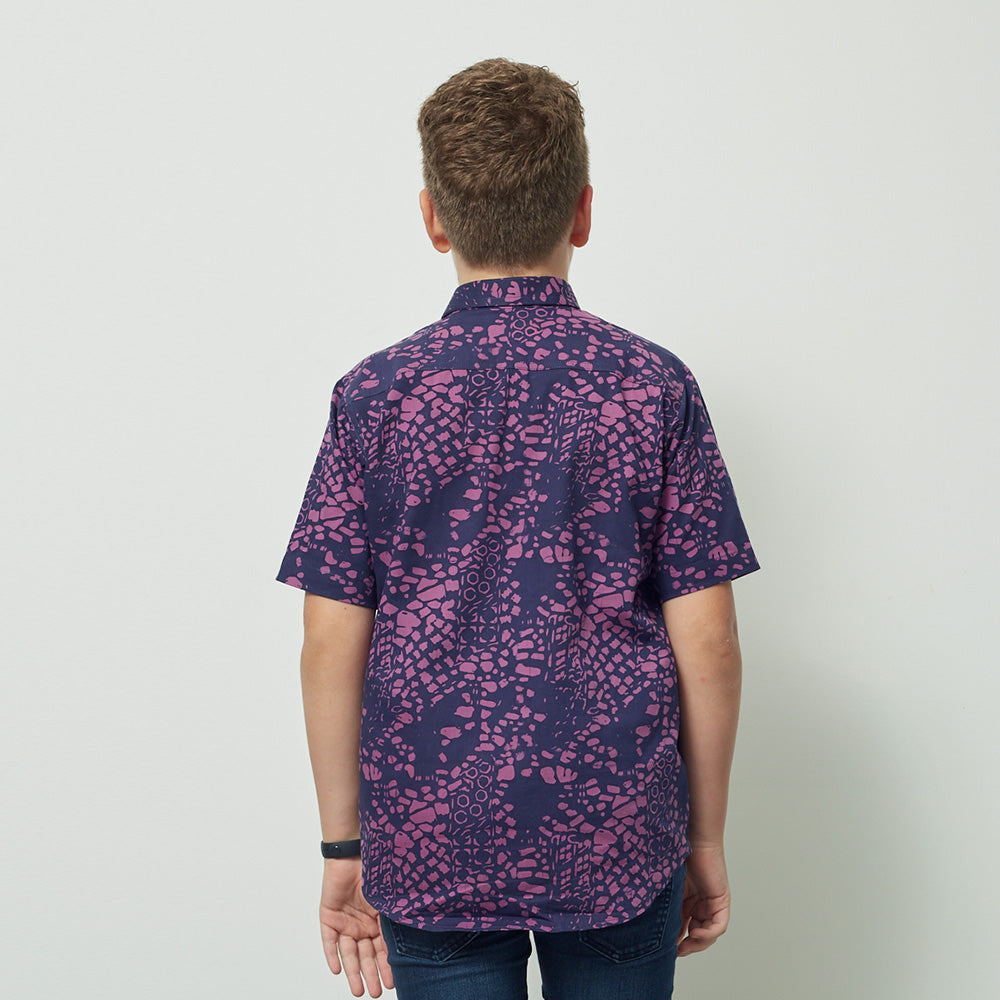 A boy wearing batik shirt in purple bintik pattern