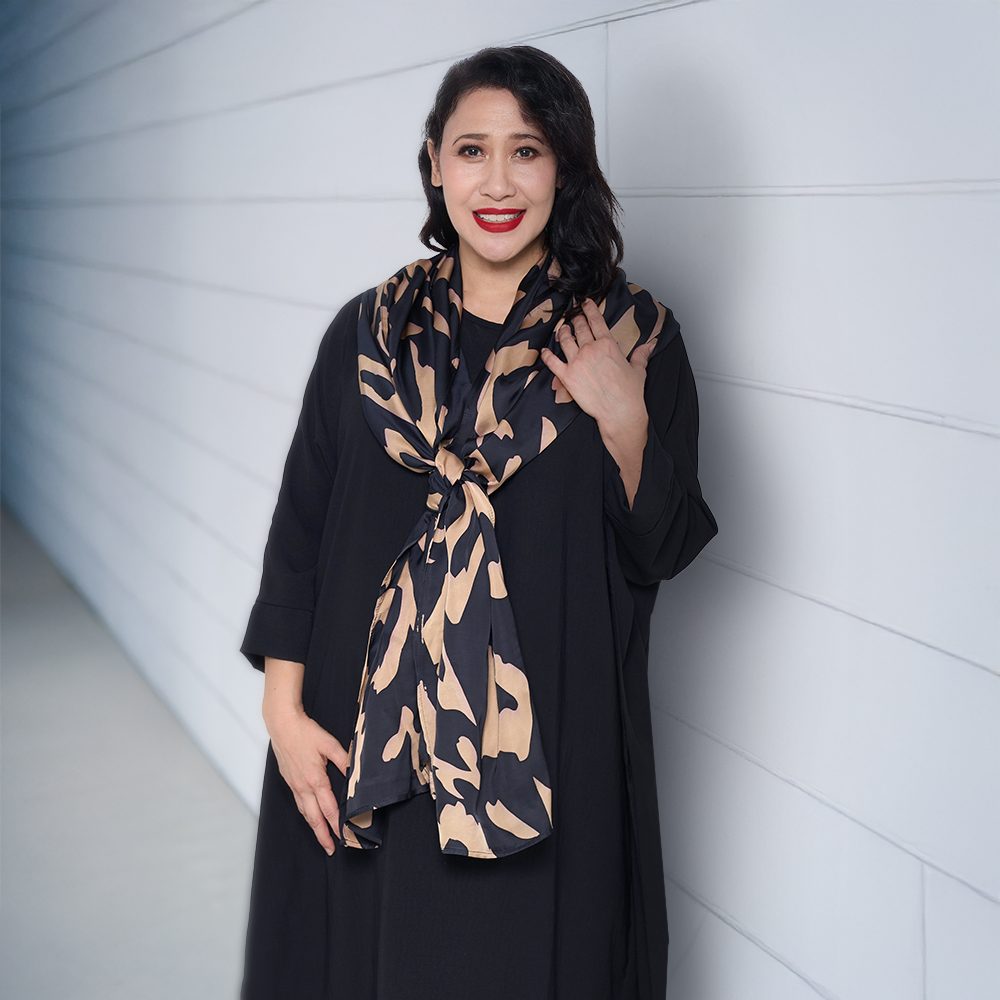 a woman wearing a black rimba scarf infront of a  plain wall