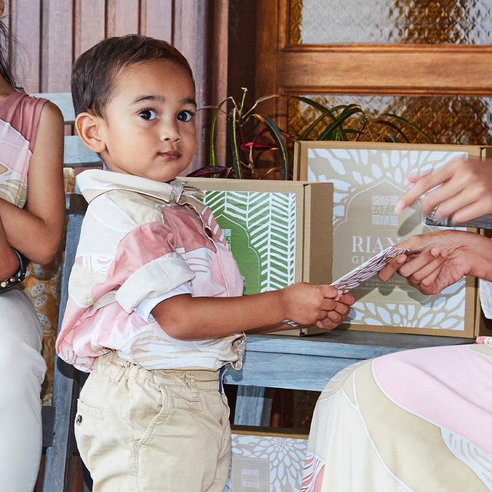 Young boy posing for his duit Raya envelope of money at Hari Raya to receive from his mother. Boy is wearing pink batik shirt size S.