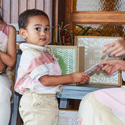 Young boy posing for his duit Raya envelope of money at Hari Raya to receive from his mother. Boy is wearing pink batik shirt size S.