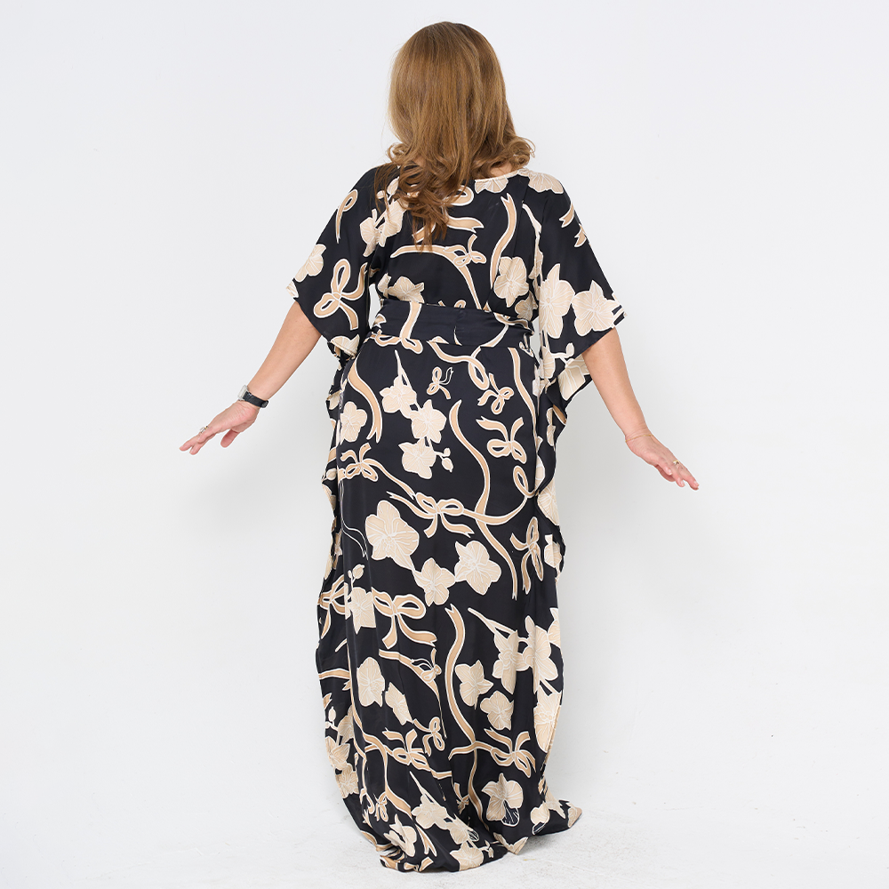 a woman poses in batik caftan dress against a white background in the pattern onyx fleur