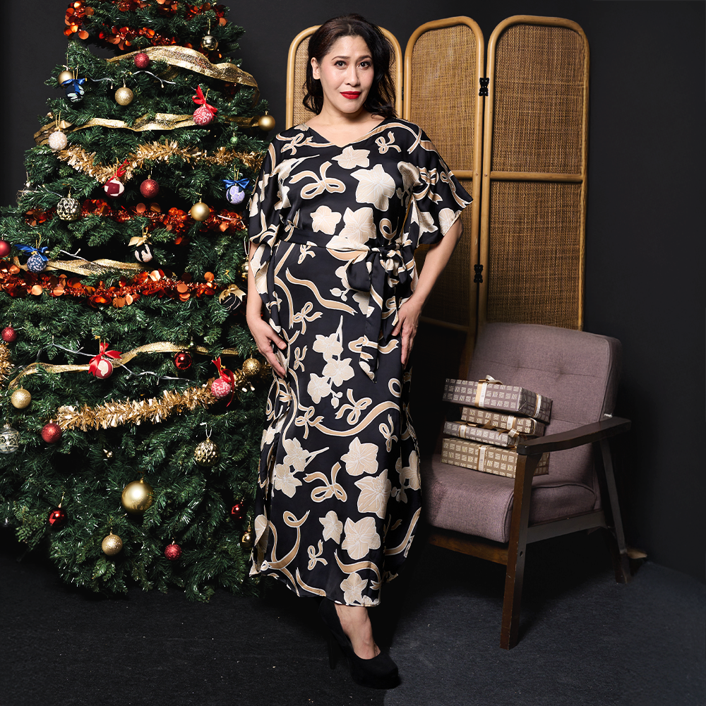 a woman posing in a christmas setting in a batik caftan dress 