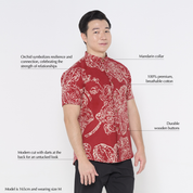 a man wearing a batik shirt in the pattern crimson orchid against a white background