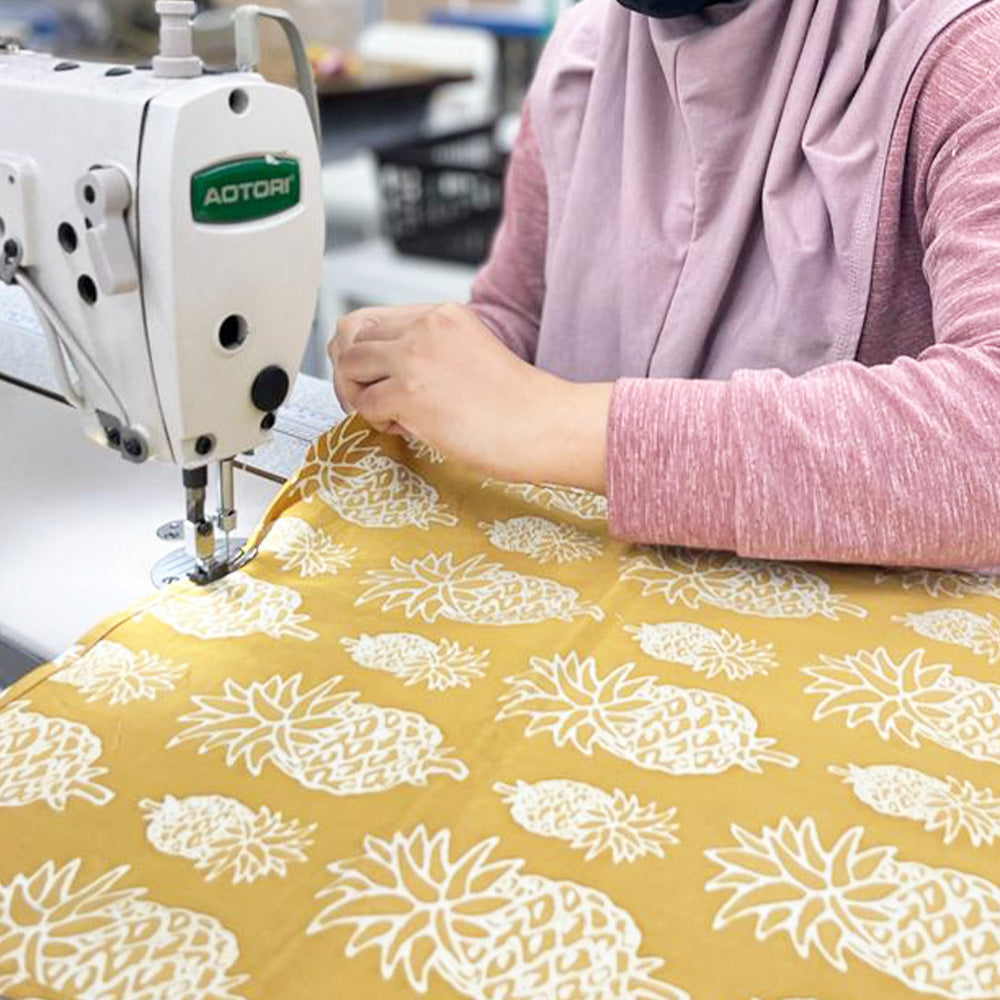 a photo a seamstress in the process of sewing authentic batik cloth to be made into homeware products