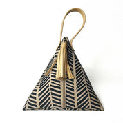 Front view of Batik Boutique’s triangular Ketupat Bag in Black Banana Leaf design with tan handle and tassel.