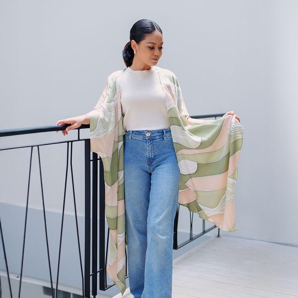 Model wearing Batik Boutique's Moss Bukit batik kimono in an airy lifestyle setting, showcasing its drape and pastel green tones