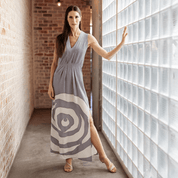 Woman in a sleeveless dress with a geometric pattern standing in a modern interior setting. MAXIDRESS SILVERROSE.