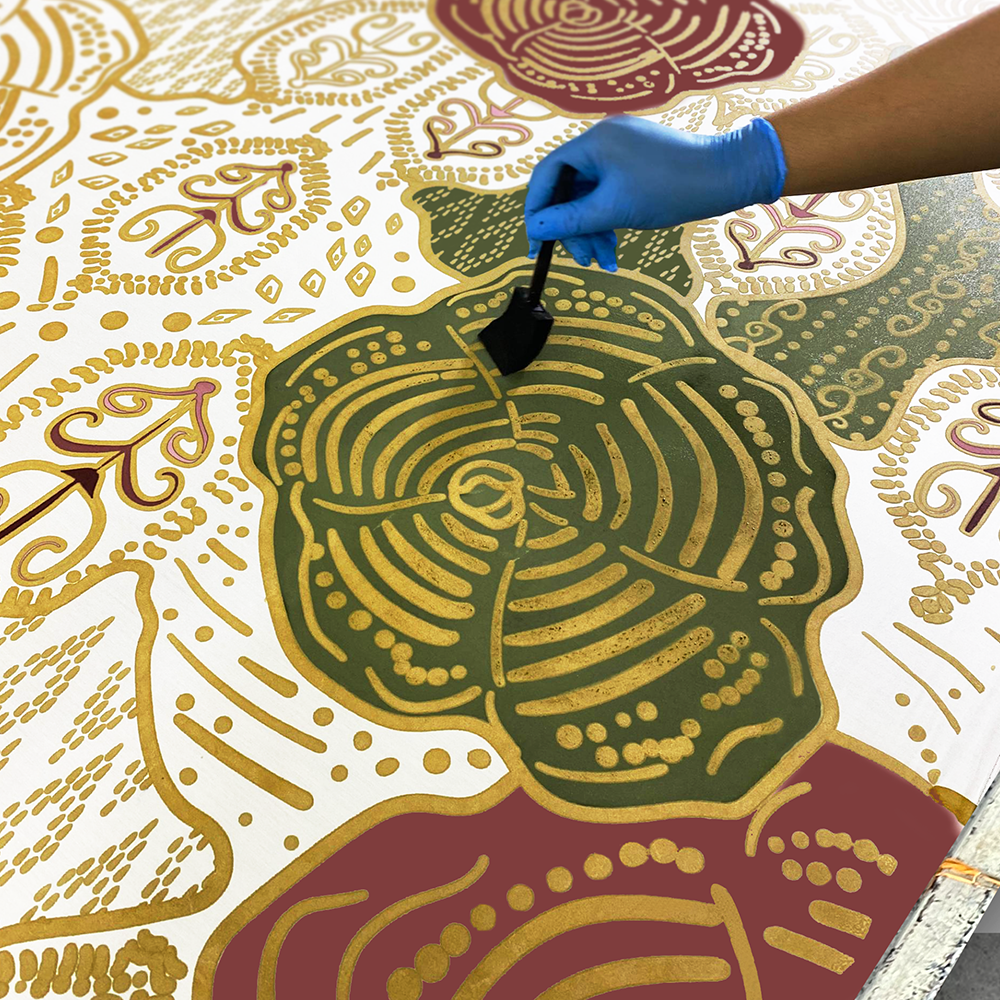 Artisan hand-painting the Maroon Petola batik design with intricate wax work