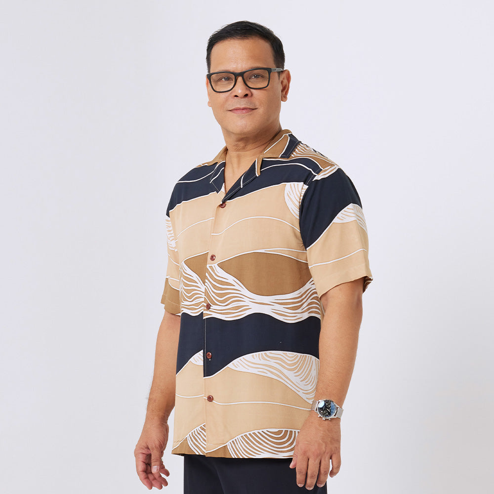 a man standing in front of white background styling batik cuban shirt in black bukit pattern 