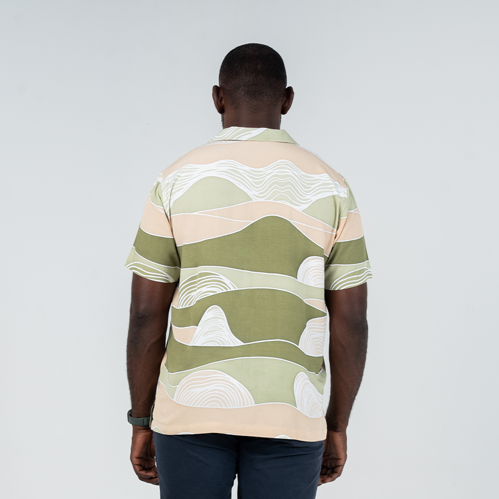 Back view of a men's Cuban batik shirt in Moss Bukit design, featuring soft green, beige, and white hand-drawn hills inspired by Malaysia's natural landscapes