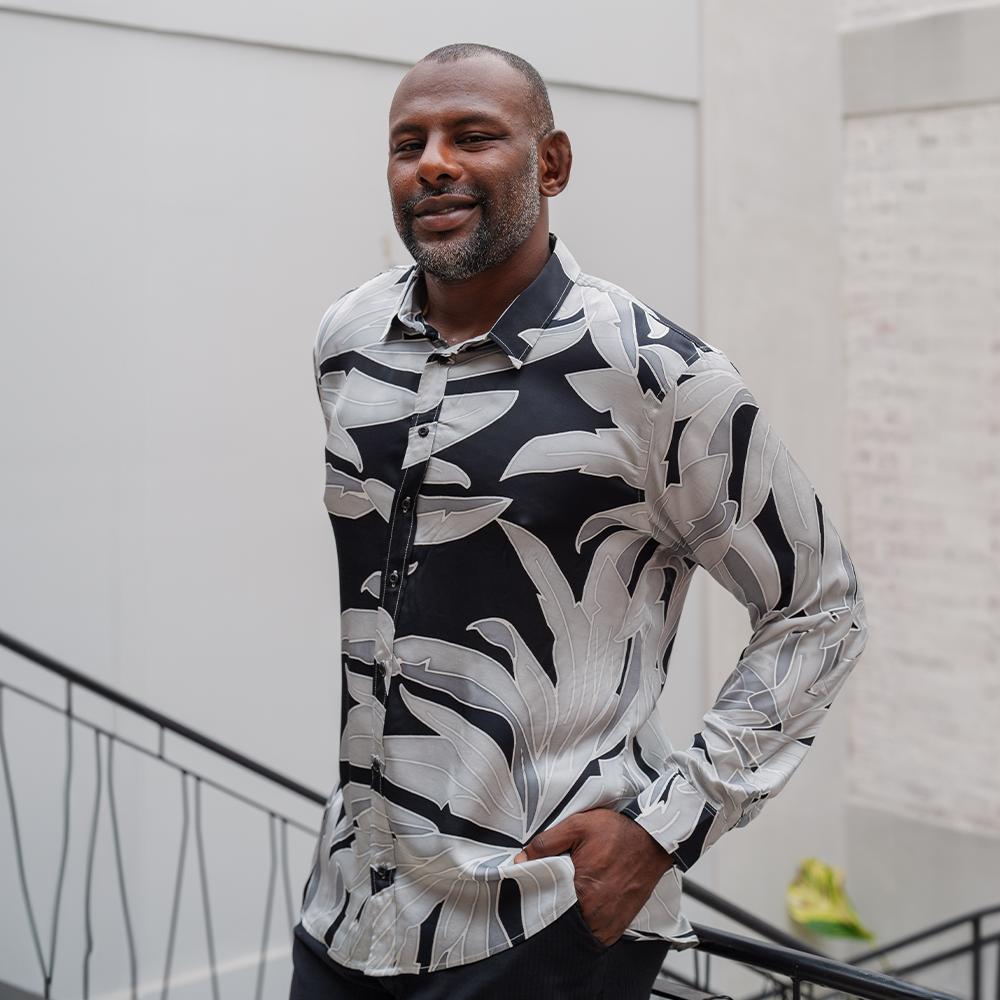 a man wearing a silk cotton shirt in the pattern starry palma in a lifestyle photo