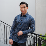 a man wearing a batik shirt in the pattern navy anyam in long sleeved in deep blue color in a lifestyle photo