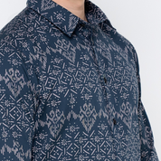 a closeup of a batik shirt in the pattern navy anyam against a white background