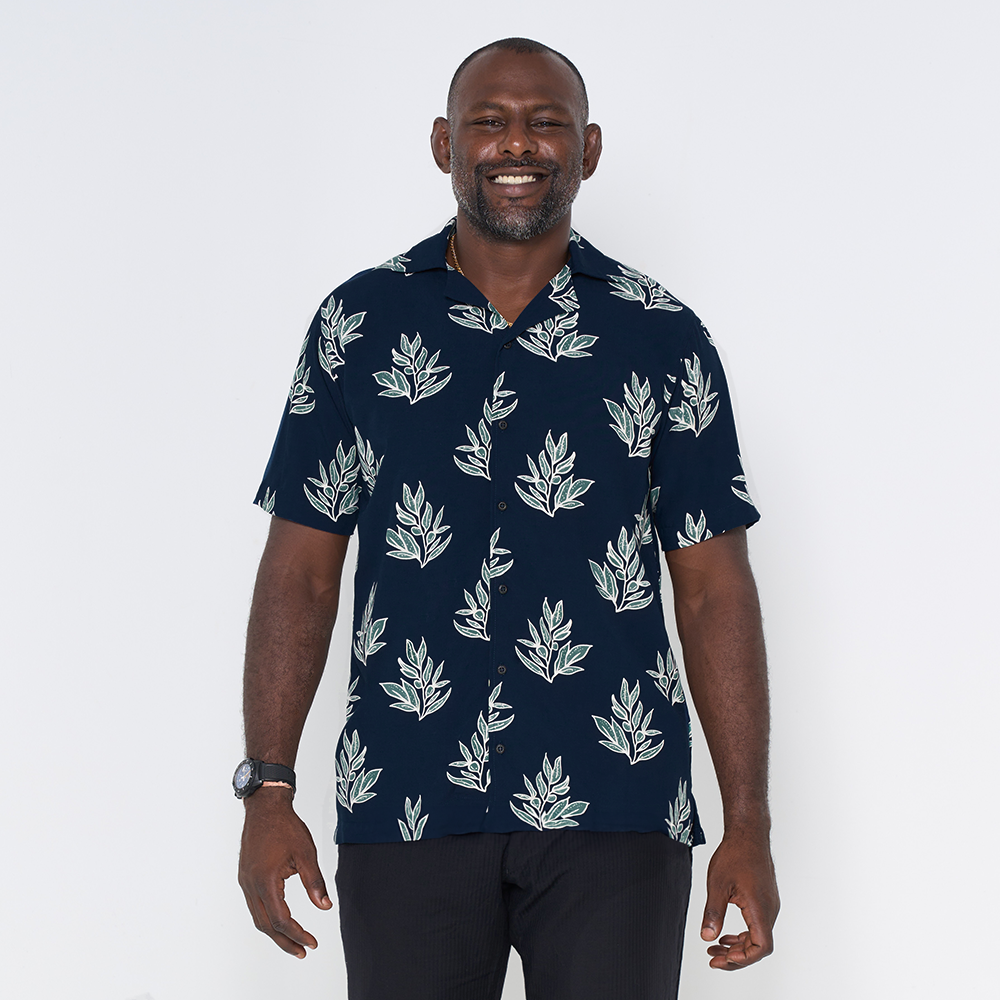 a man posing in a batik shirt in the pattern navy olive leaf