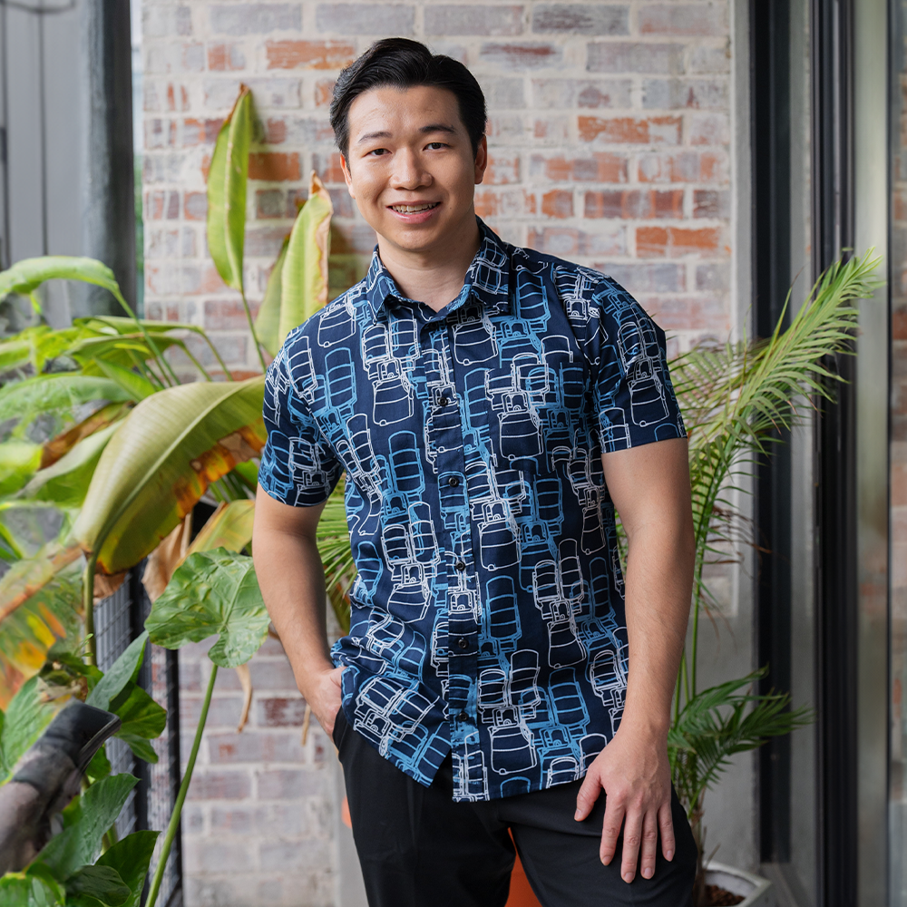 a male model poses in a batik shirt in the pattern navy tiffin in a lifestyle photo