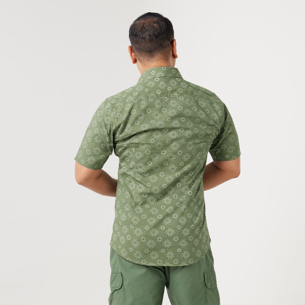 a male model posing with the back of a batik shirt in the pattern olive bintang against a white background