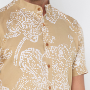 a man wearing tan orchid batik shirt closeup against a white background