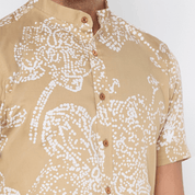 a man wearing tan orchid batik shirt closeup against a white background