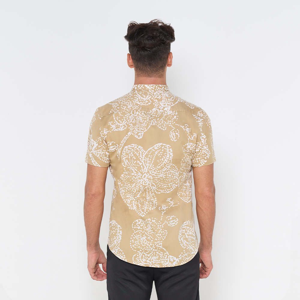 a man wearing a batik shirt against a white background in the pattern tan orchid showcasing the details on the back