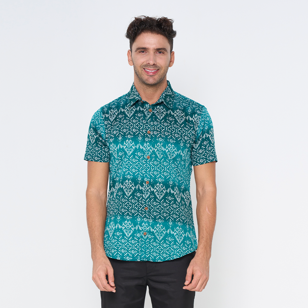 a man wearing a batik shirt in the pattern turquoise anyam against the white background