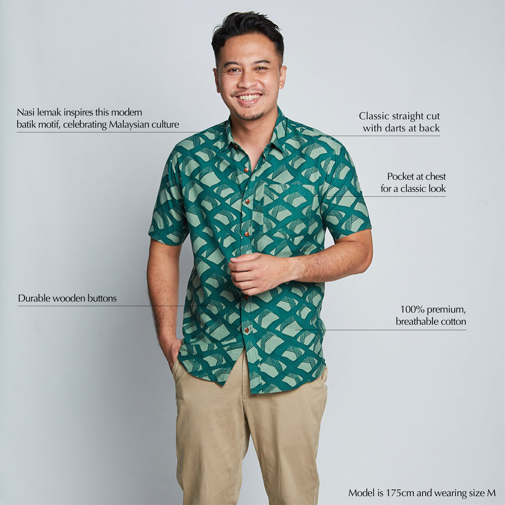 a male model posing in front of a neutral background while wearing a  batik shirt in the pattern green nasi lemak
