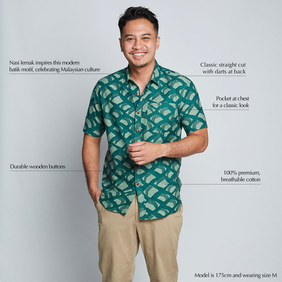 a male model posing in front of a neutral background while wearing a  batik shirt in the pattern green nasi lemak