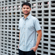 Model in Grey Anyam batik shirt, standing against a concrete wall