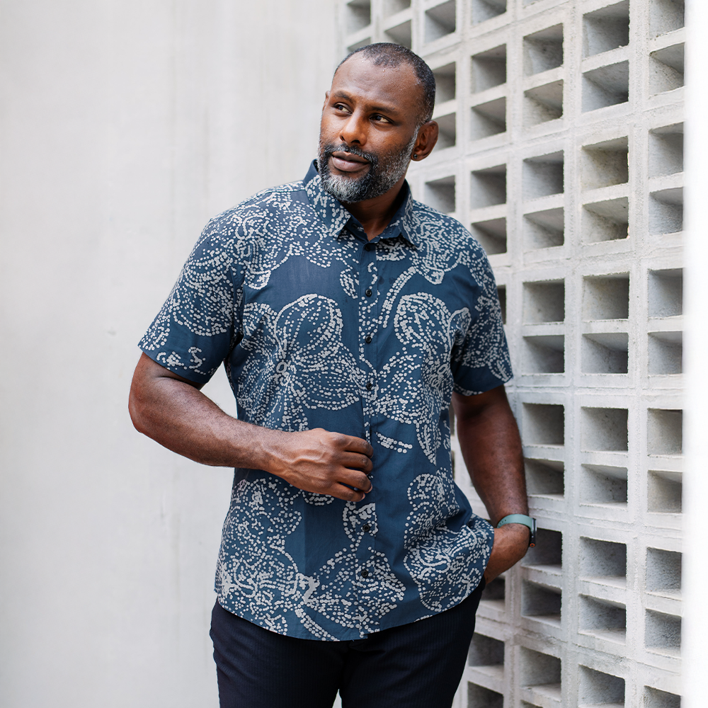 Man wearing navy batik orchid shirt styled casually outdoors, highlighting its modern Malaysian craftsmanship