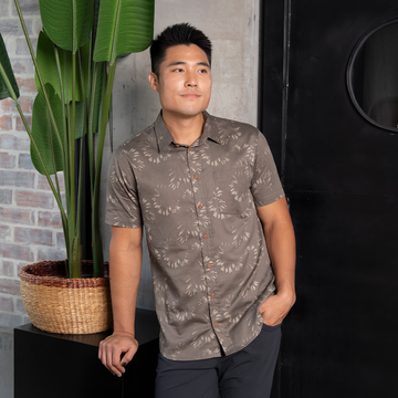 a lifestyle photo of a man wearing a batik shirt in the pattern stone paw atilia haron collection