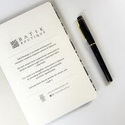 Batik-Inspired Notebook & Pen - Black Floret note book opened and showing the first page with a pen that comes along with the set 